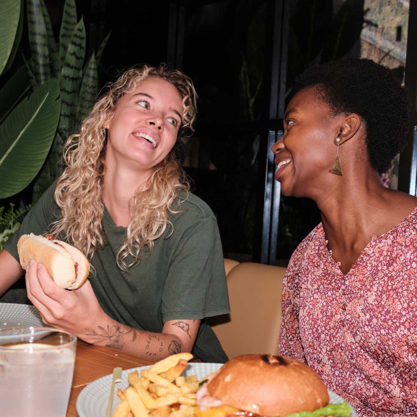 Två kvinnor samtalar vid ett restaurangbord i Motala, där sociala möten och samtal utvecklar vänskaper.