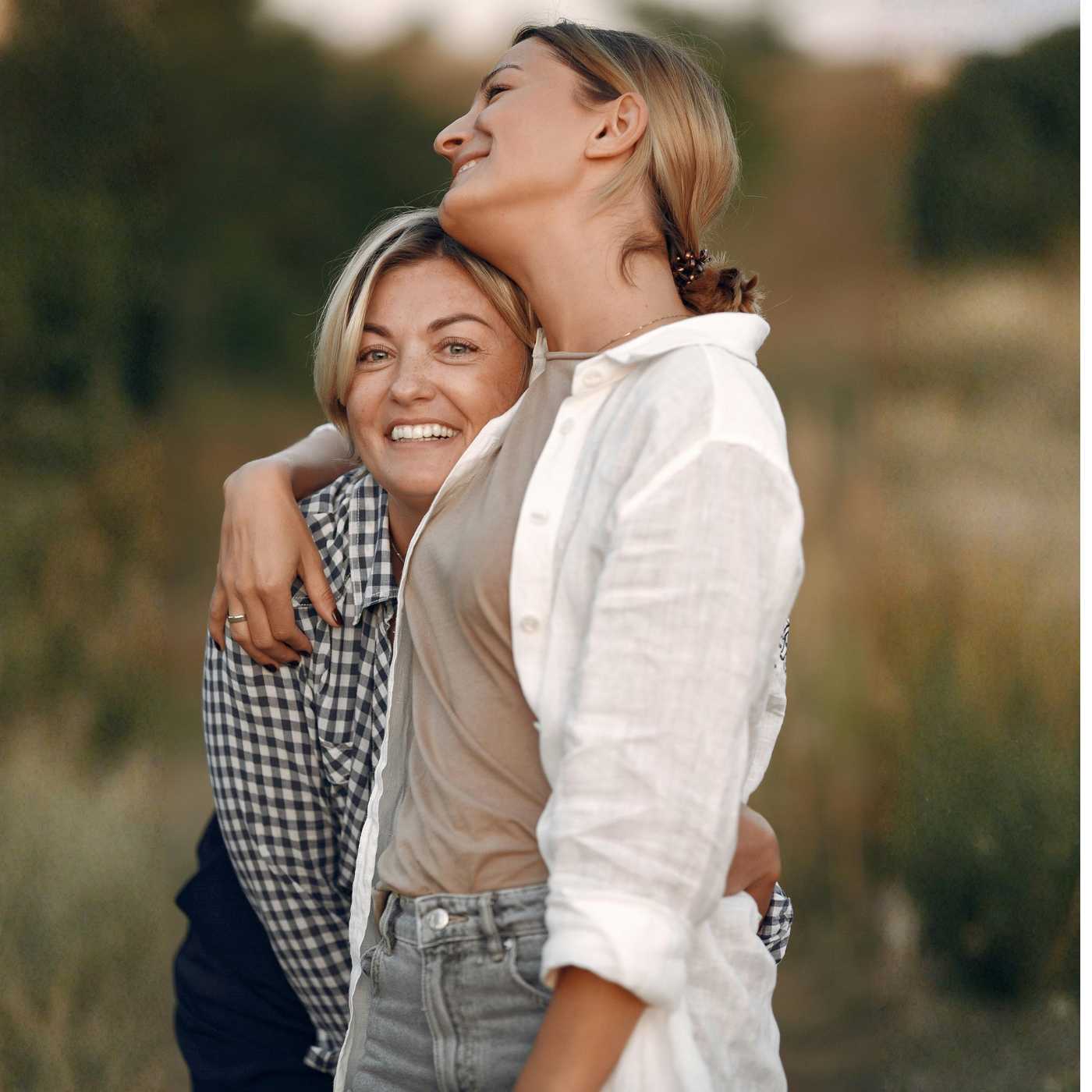 Två kvinnor kramas och umgås tillsammans i naturen kring Helsingborg, vilket symboliserar nära vänskap och trygg gemenskap.