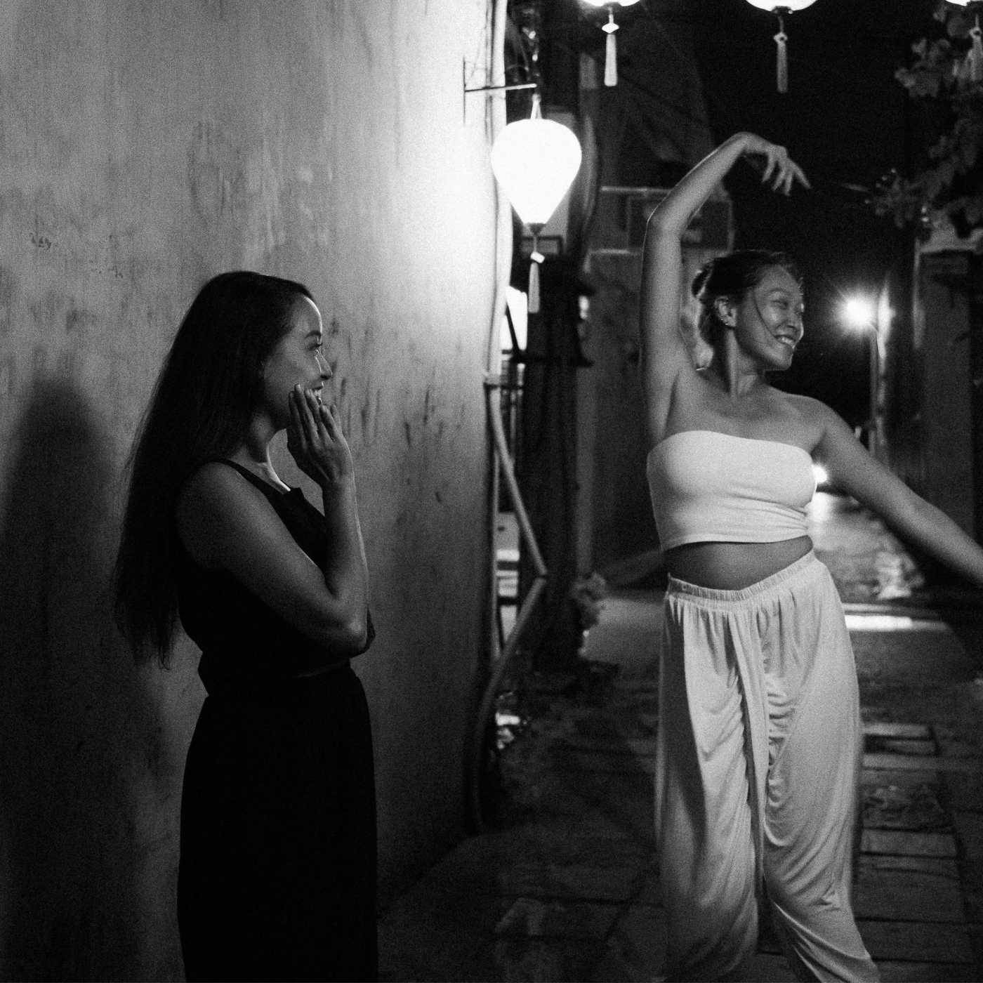 Två kvinnor skrattar och dansar tillsammans under en kvällspromenad i Härlanda, vilket speglar glädjen i att träffa nya vänner och bygga social gemenskap