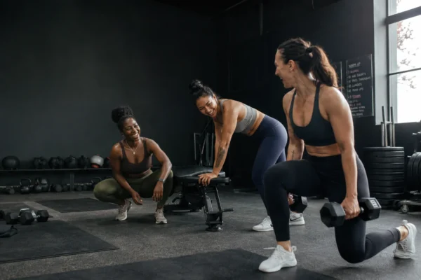 hitta träningskompis – tre kvinnor tränar tillsammans på gym och skrattar