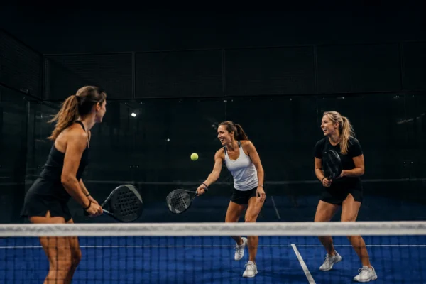 hitta padelkompisar – tre tjejer spelar padel tillsammans på inomhusplan