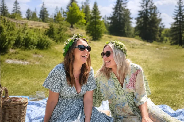 Två kvinnor sitter tillsammans på en picknickfilt en sommardag i Norrtälje efter att ha hittat nya vänner genom Gofrendly.