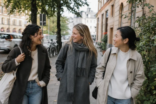 hitta vänner online – tre kvinnor promenerar och skrattar tillsammans på en stadsgata